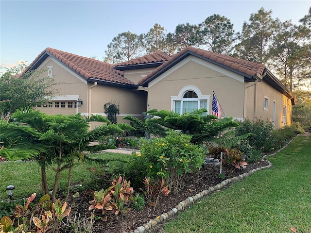 mediterranean / spanish-style house featuring a tiled roof, an attached garage, and stucco siding