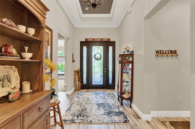 foyer with light wood-type flooring, baseboards, a chandelier, and crown molding