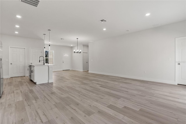 unfurnished living room featuring light wood finished floors, a sink, visible vents, and recessed lighting