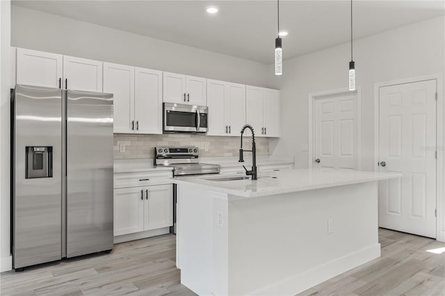 kitchen with light wood-style flooring, a sink, white cabinets, appliances with stainless steel finishes, and backsplash