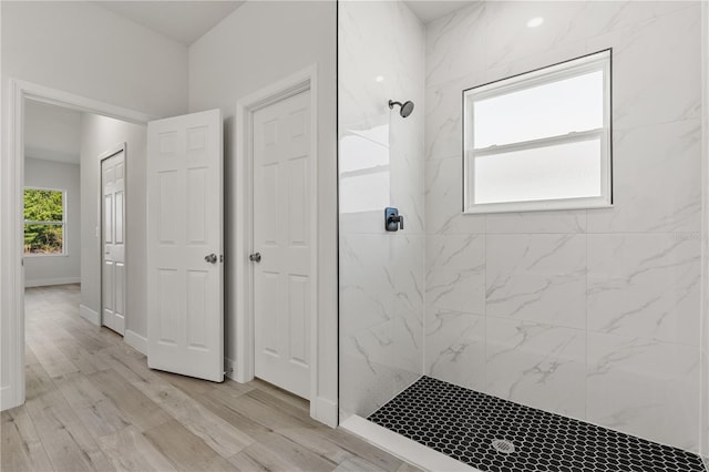 full bath featuring a marble finish shower, baseboards, and wood finished floors