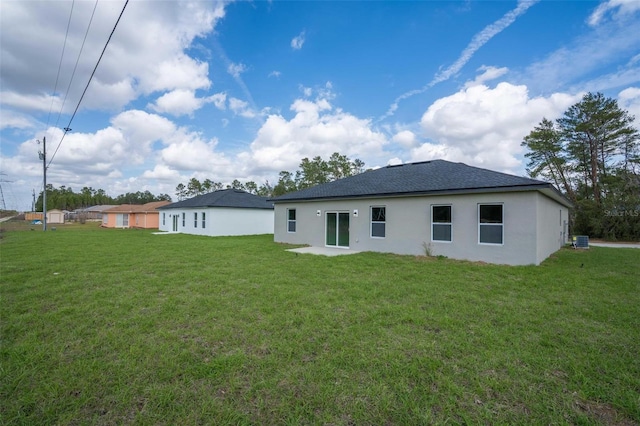 back of property featuring cooling unit, roof with shingles, and a yard