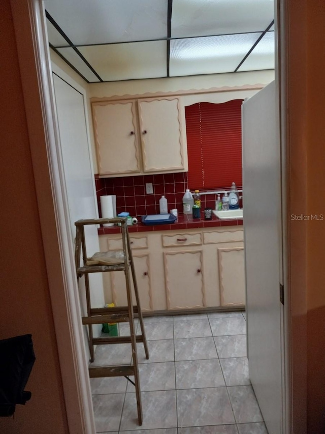 kitchen featuring tile countertops, cream cabinets, decorative backsplash, and light tile patterned flooring