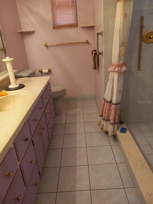 full bathroom featuring tile patterned flooring, tiled shower, vanity, and toilet