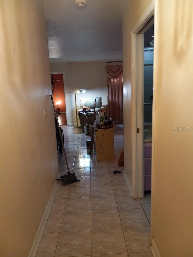 hallway with baseboards and tile patterned floors