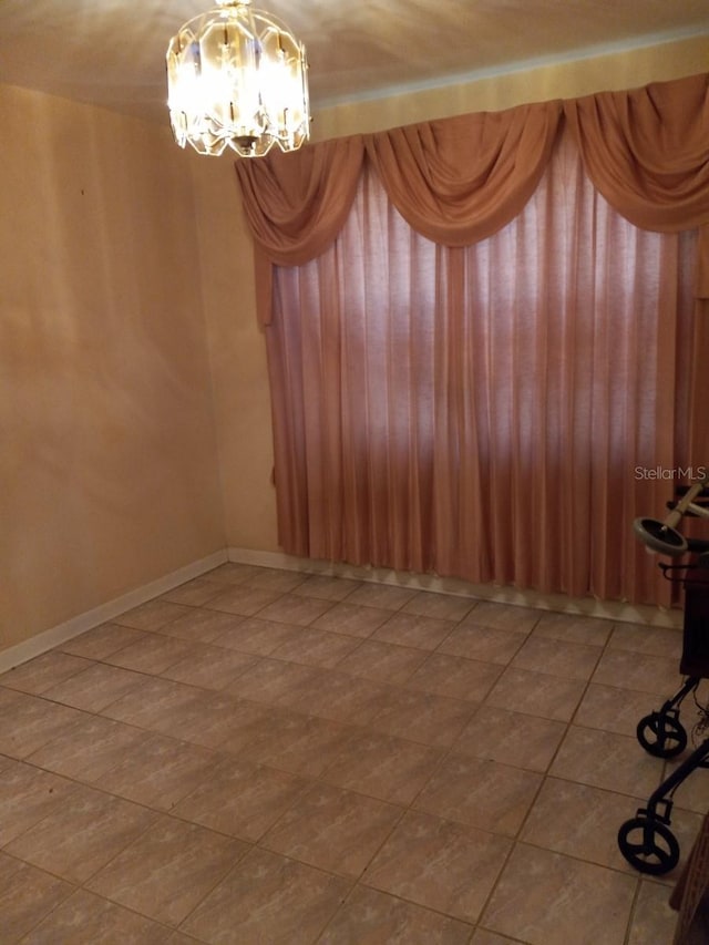 empty room with a notable chandelier and baseboards