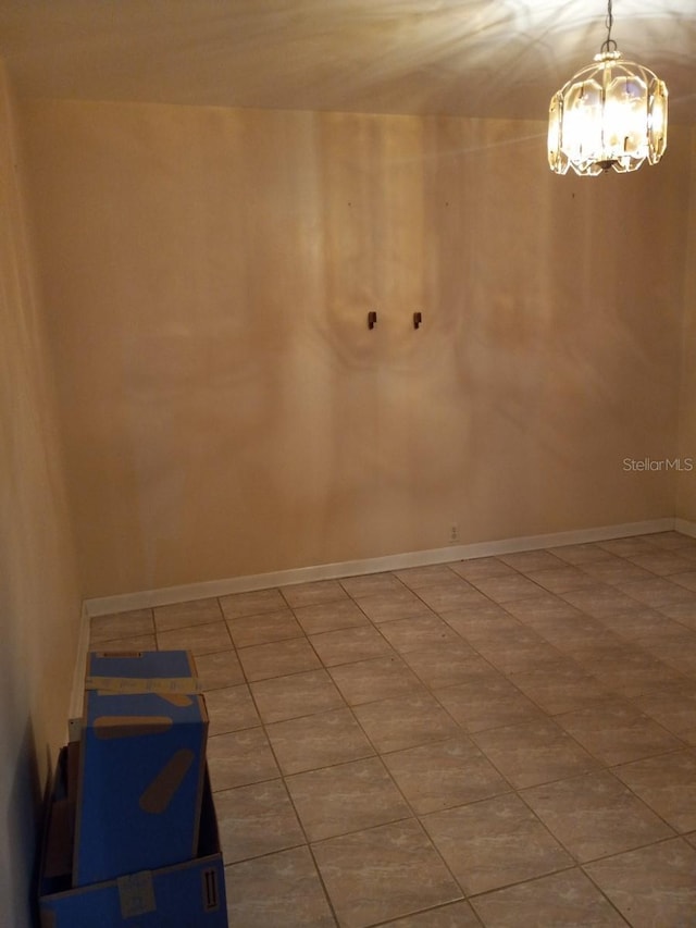 unfurnished room featuring baseboards and an inviting chandelier