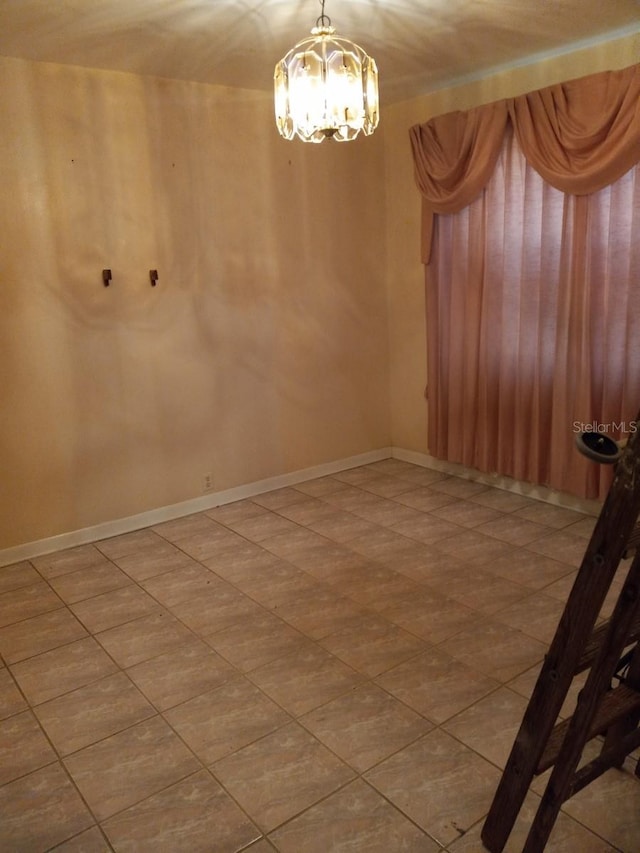 spare room featuring baseboards and a notable chandelier