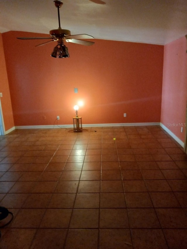 spare room featuring lofted ceiling, tile patterned flooring, baseboards, and a ceiling fan