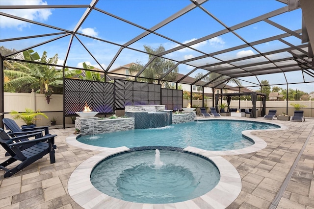 pool with glass enclosure, a patio area, fence, and an in ground hot tub