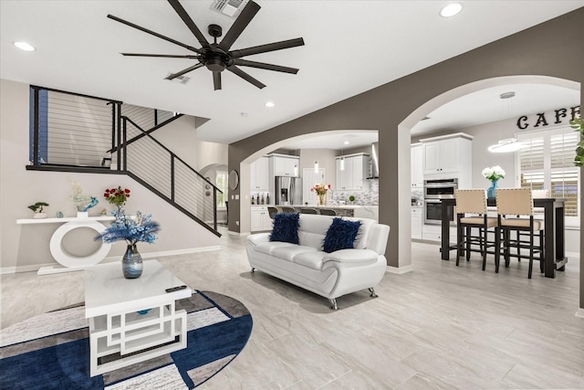 living room featuring arched walkways, stairway, baseboards, and recessed lighting