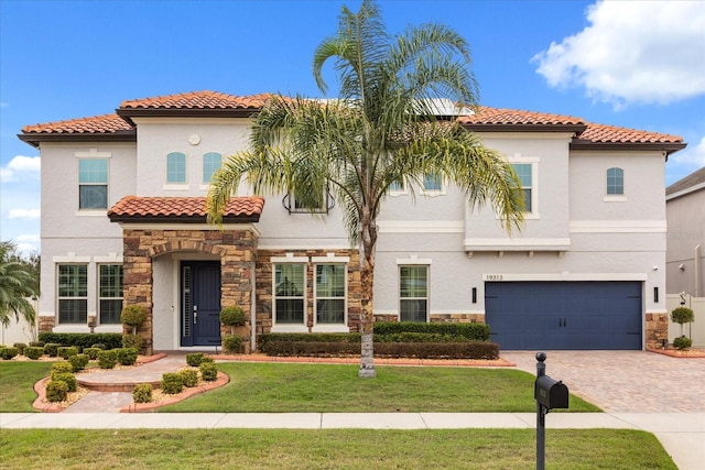 mediterranean / spanish-style home with stone siding, a front lawn, and stucco siding