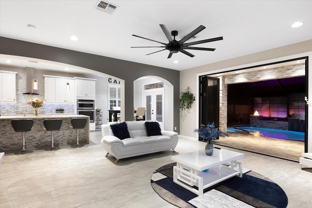 living area with visible vents, arched walkways, baseboards, ceiling fan, and recessed lighting