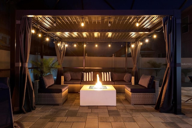 patio at night featuring fence and an outdoor living space