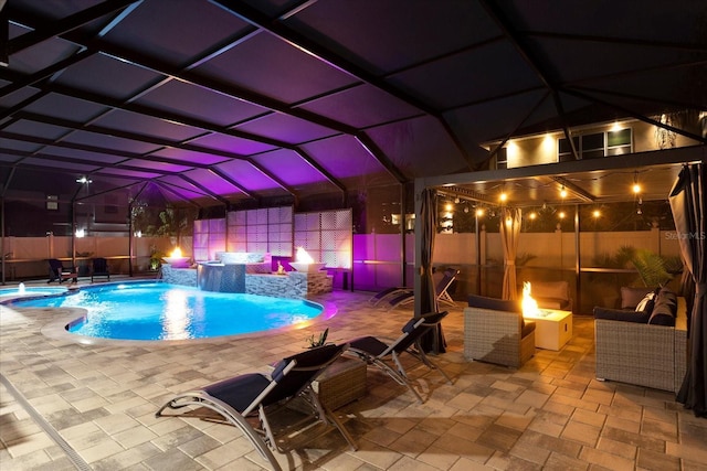 pool at twilight with a patio, a fenced backyard, a lanai, a fire pit, and a pool with connected hot tub