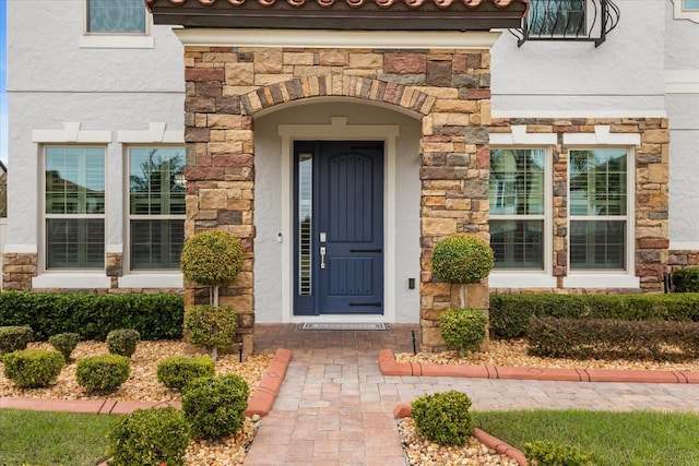 view of exterior entry with stone siding and stucco siding