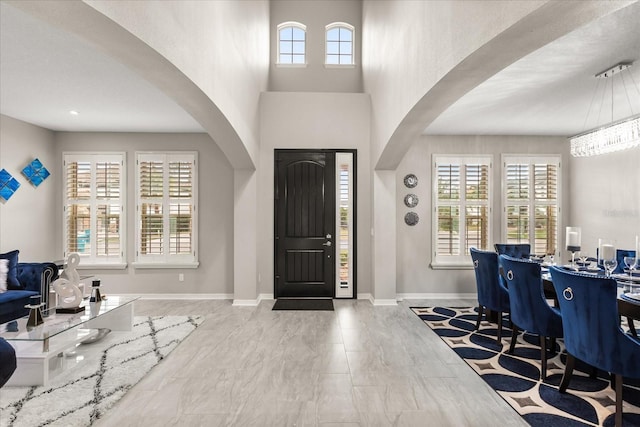 foyer with a healthy amount of sunlight, baseboards, and arched walkways