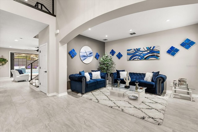 living area with arched walkways, recessed lighting, visible vents, a high ceiling, and baseboards