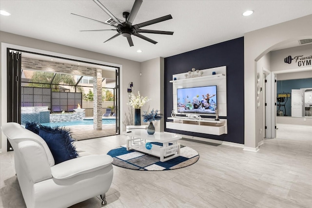 living room featuring arched walkways, recessed lighting, visible vents, a ceiling fan, and baseboards