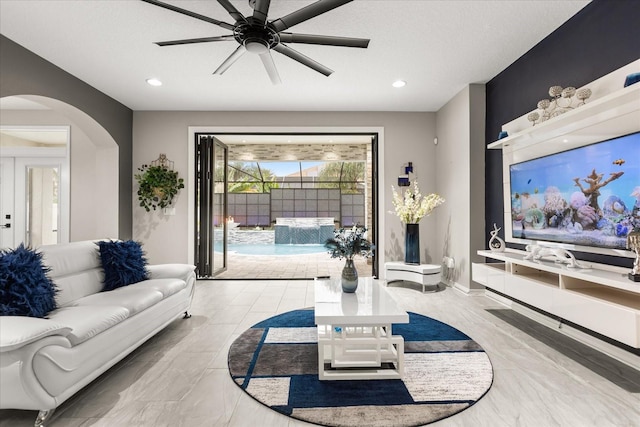 living area with a ceiling fan, arched walkways, baseboards, and recessed lighting