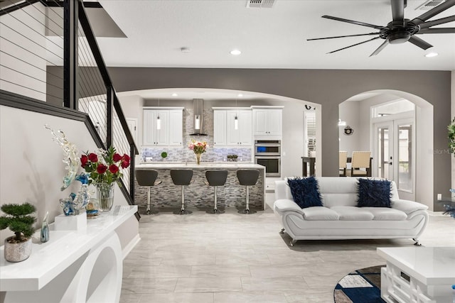 living area featuring a ceiling fan, arched walkways, french doors, and recessed lighting