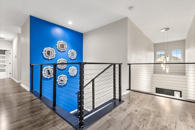 corridor featuring wood finished floors, an upstairs landing, and baseboards