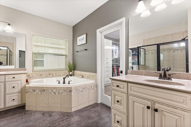 bathroom with wood finished floors, a stall shower, a garden tub, and vanity