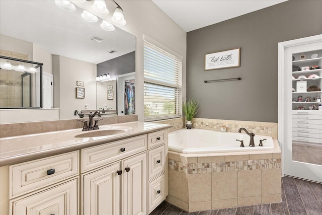 full bathroom with a garden tub, visible vents, wood finished floors, and vanity