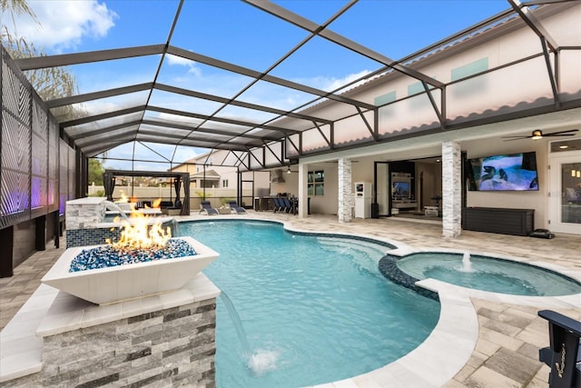 view of pool featuring a pool with connected hot tub, glass enclosure, a patio, and ceiling fan