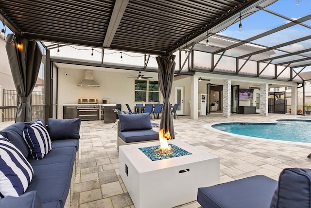 view of patio featuring an outdoor pool, an outdoor living space with a fire pit, glass enclosure, ceiling fan, and exterior kitchen