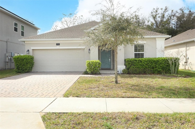 ranch-style home with a garage, a shingled roof, decorative driveway, stucco siding, and a front lawn