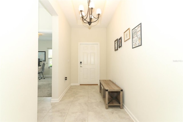 entryway with light tile patterned flooring, a notable chandelier, and baseboards