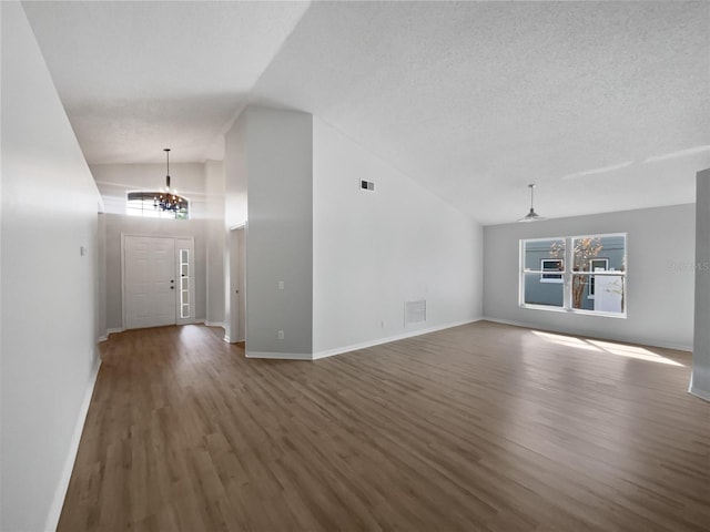 unfurnished living room with a textured ceiling, wood finished floors, visible vents, and an inviting chandelier