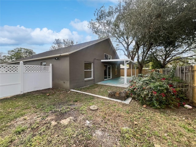 rear view of house featuring a patio, a fenced backyard, and stucco siding