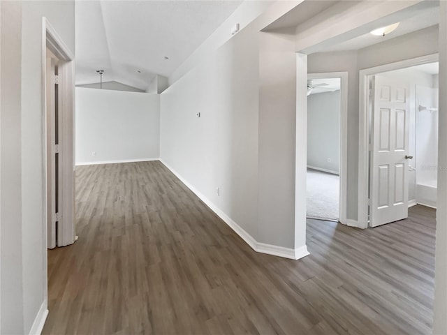 hall featuring baseboards, vaulted ceiling, and wood finished floors