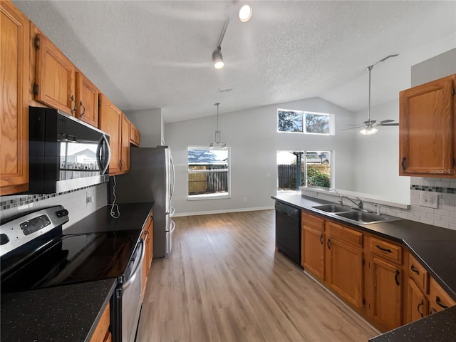 kitchen featuring a sink, vaulted ceiling, a wealth of natural light, black appliances, and dark countertops