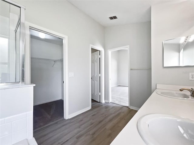 bathroom featuring wood finished floors, an enclosed shower, a sink, and visible vents