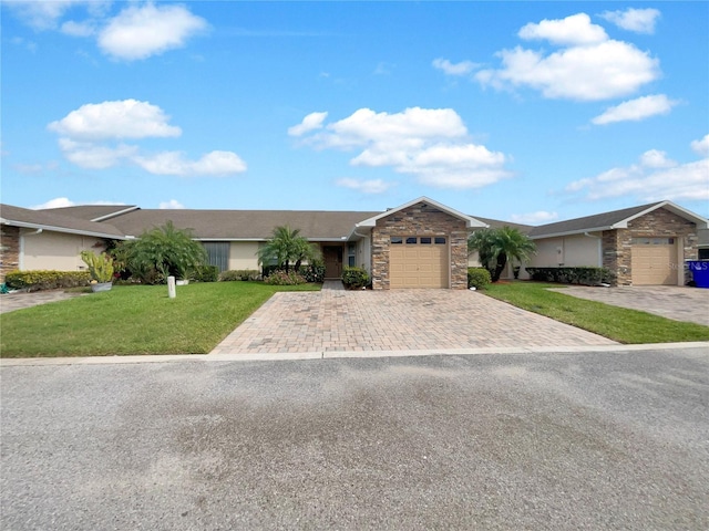 single story home featuring a garage, stone siding, a front lawn, and decorative driveway