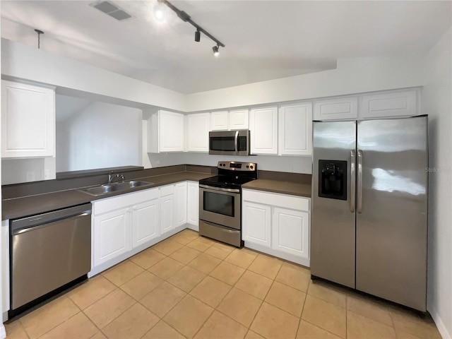 kitchen featuring visible vents, white cabinets, dark countertops, stainless steel appliances, and a sink