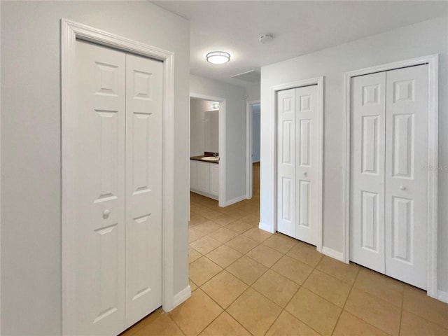 corridor featuring light tile patterned flooring and baseboards