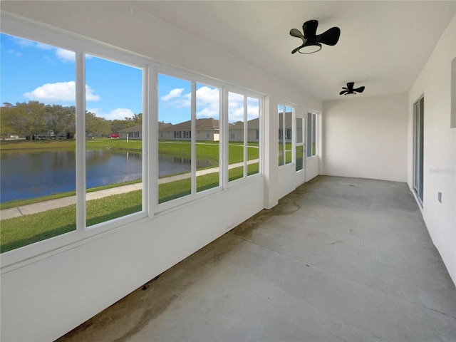 unfurnished sunroom with ceiling fan and a water view