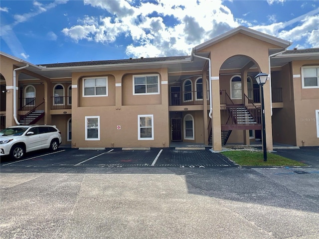 view of building exterior featuring stairs and uncovered parking