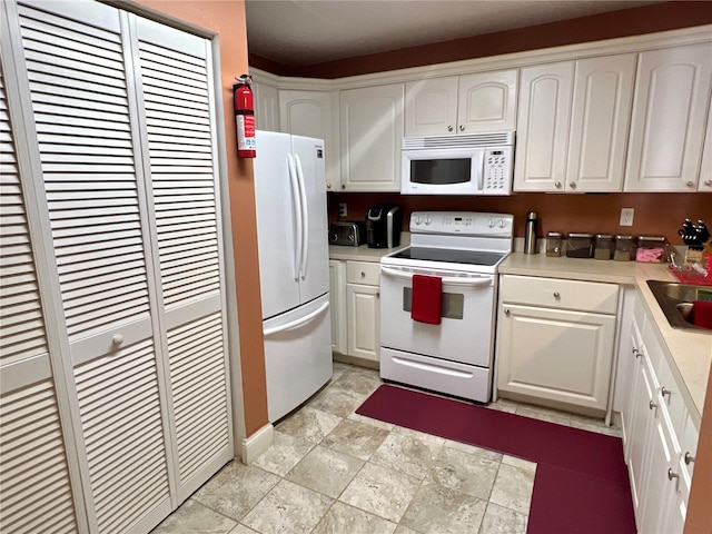 kitchen featuring white appliances, white cabinetry, light countertops, and a sink