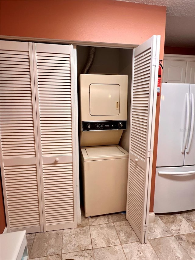 laundry room with stacked washer / drying machine, laundry area, and a textured ceiling