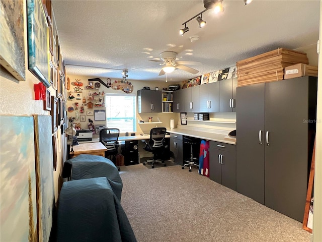 home office with a textured ceiling, carpet flooring, built in study area, and a ceiling fan