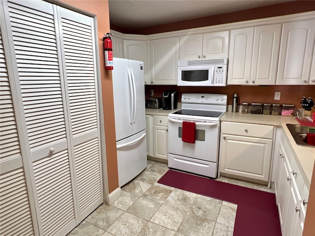 kitchen with a sink, light countertops, white cabinetry, and white appliances