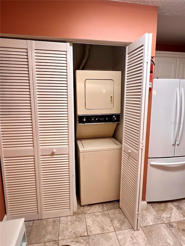 laundry room with stacked washer / drying machine, stone finish flooring, and laundry area