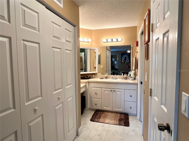 bathroom with connected bathroom, vanity, a textured ceiling, marble finish floor, and visible vents