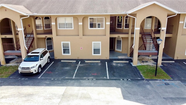 view of property featuring uncovered parking and stairs