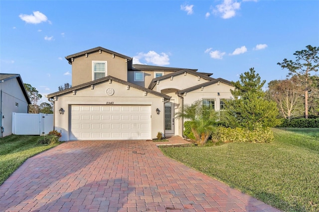 mediterranean / spanish house featuring a garage, a gate, fence, decorative driveway, and stucco siding